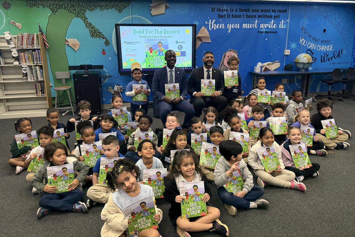 Students at Pembroke Lakes Elementary school hold copies of “See Marcus Grow” alongside Broward County Public Schools Superintendent Howard Hepburn.