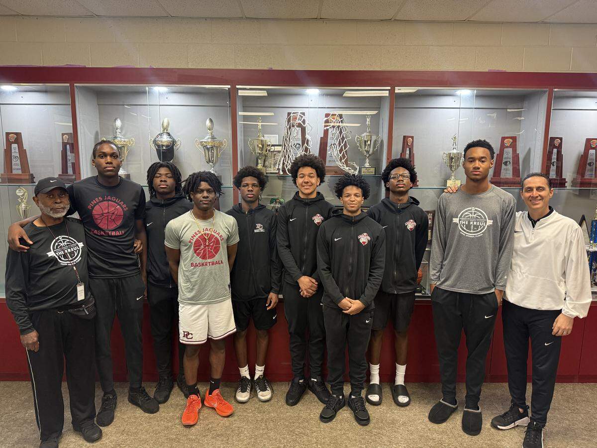 The Pembroke Pines Charter High School boys basketball team, flanked by assistant coach Kenneth Trueblood on the left and head coach Dave Roca on the right.