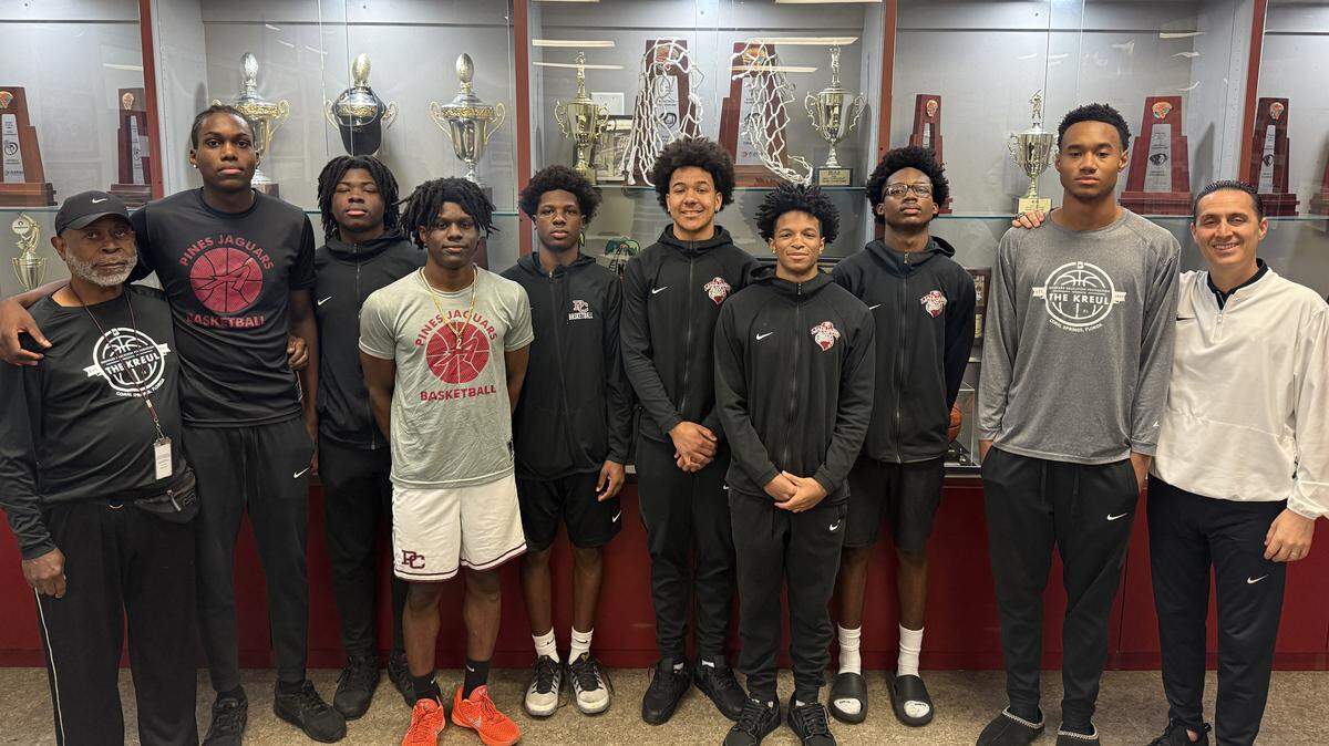 The Pembroke Pines Charter High School boys basketball team, flanked by assistant coach Kenneth Trueblood on the left and head coach Dave Roca on the right.
